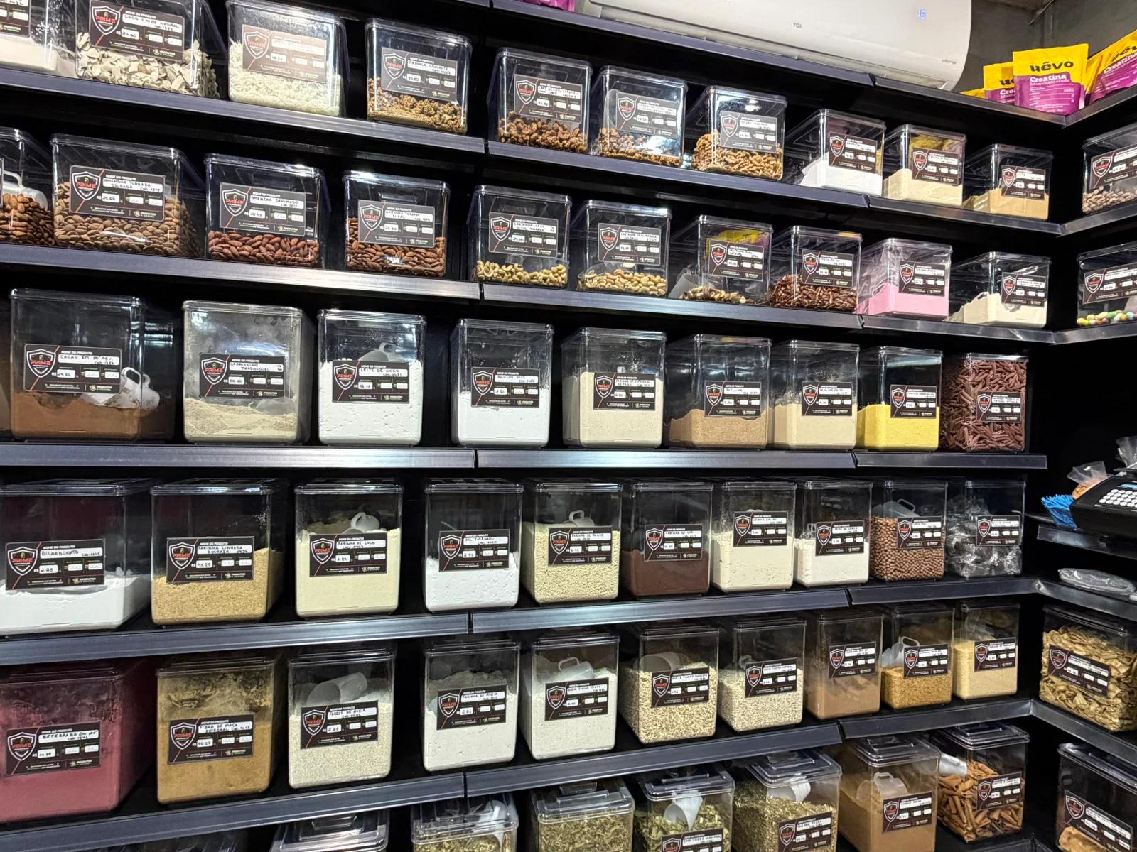 Prateleiras de produtos naturais da Prime Performance em Campo Grande MS, com castanhas, amêndoas, cacau em pó, farinhas, grãos e ervas